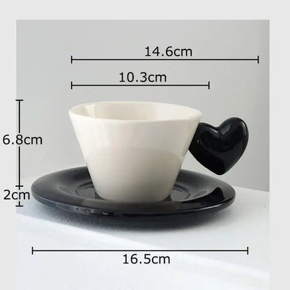 A white porcelain lovers mug with a glossy black heart shape handle on a matching black saucer in dining room