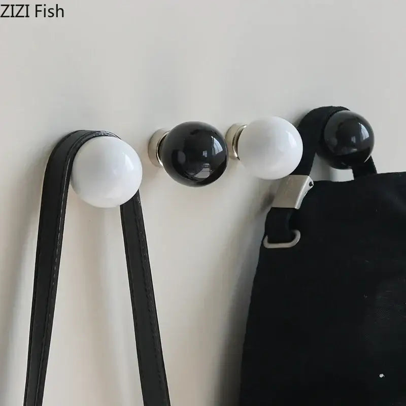 Glossy black and white ceramic spherical wall hook clothing rack with metallic bases for bedroom use