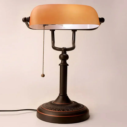 Antique bronze-finished glass banker lamp with warm amber shade and ornate base featured in decorbites lamp cover design