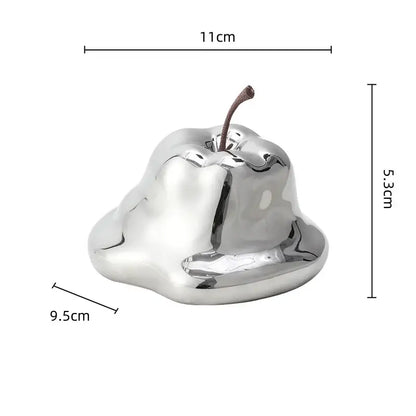 Shiny silver metallic apple-shaped decor with brown stem complementing decorbites abstract melting apple sculpture