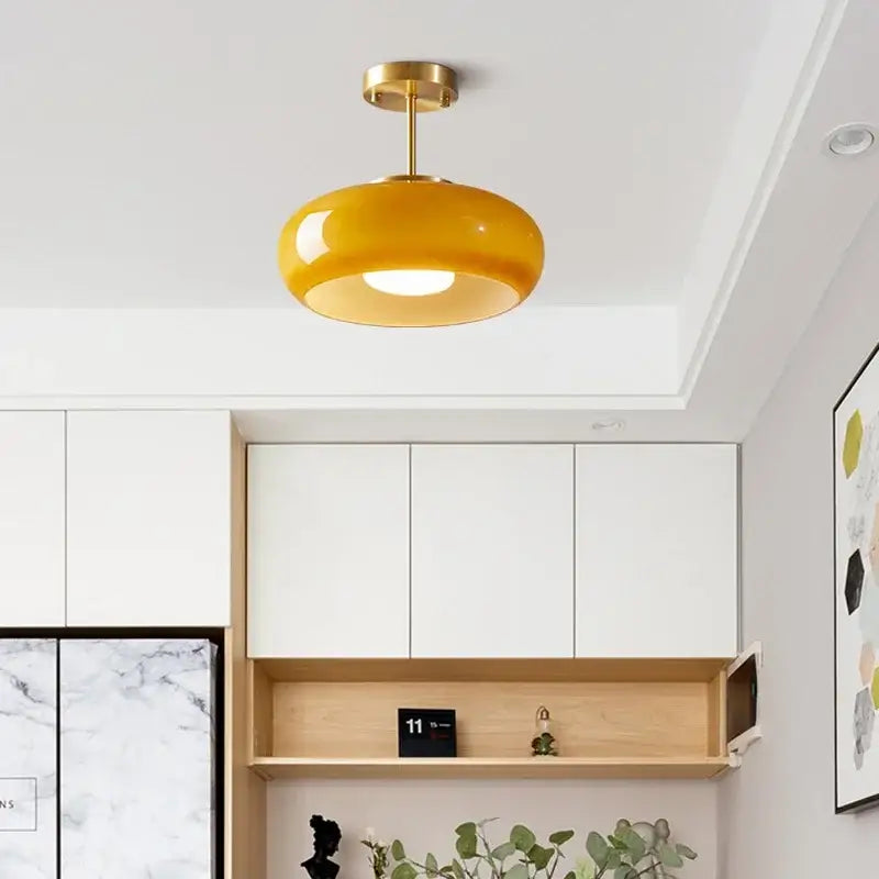 A modern yellow glass ball led pendant light with brass finish metal fixture for kitchen or dining room pendant lights