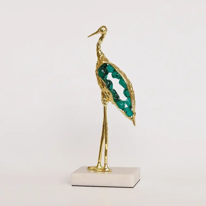 Gold and emerald crystal crane sculpture with emerald green gemstone details on white marble base for living room decor