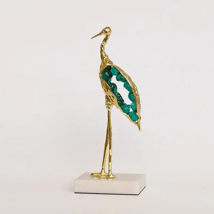 Gold and emerald crystal crane sculpture with emerald green gemstone details on white marble base for living room decor