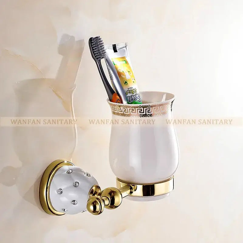 White ceramic toothbrush holder with gold-toned accents and greek key pattern in gold and white crystal bath hardware set