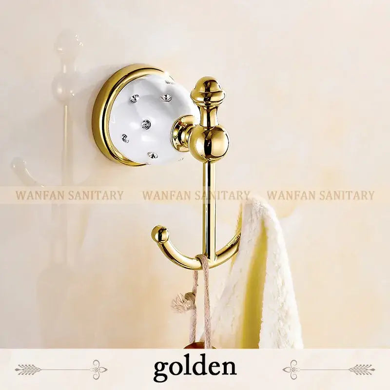 Golden bathroom hook with white ceramic base clear rhinestones and polished brass accents in bath hardware set