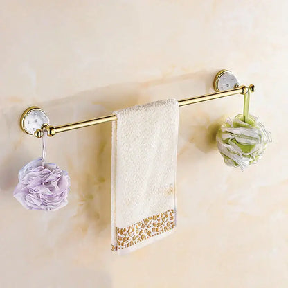 Gold-toned wall-mounted towel rack with decorative circular mounts holding white towel and floral loofahs in bath hardware set
