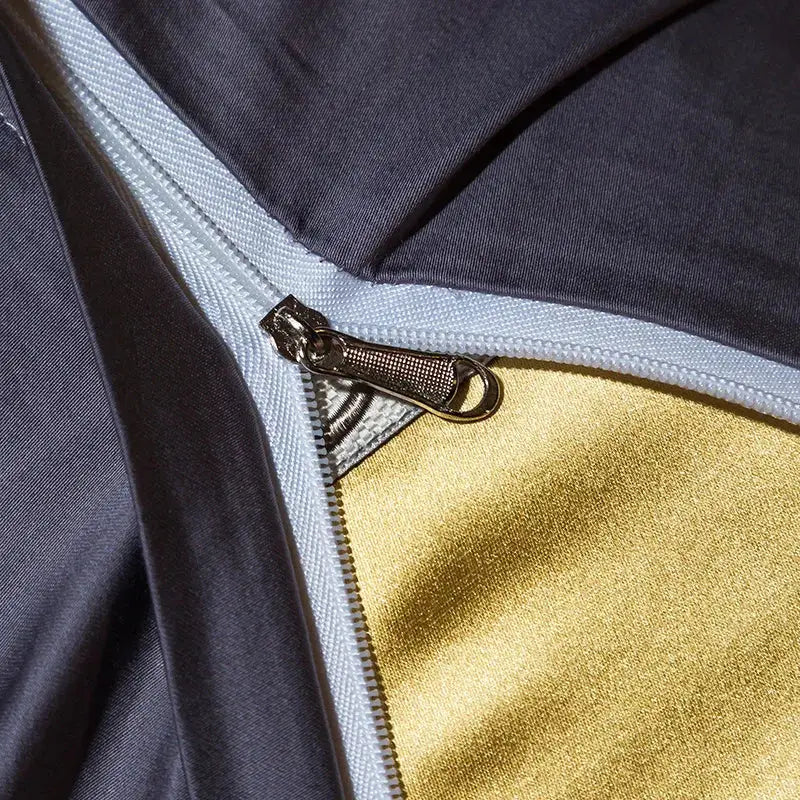 A metallic zipper with a textured pull tab on gold and black 200s embroidery egyptian cotton bedding set fabric layers