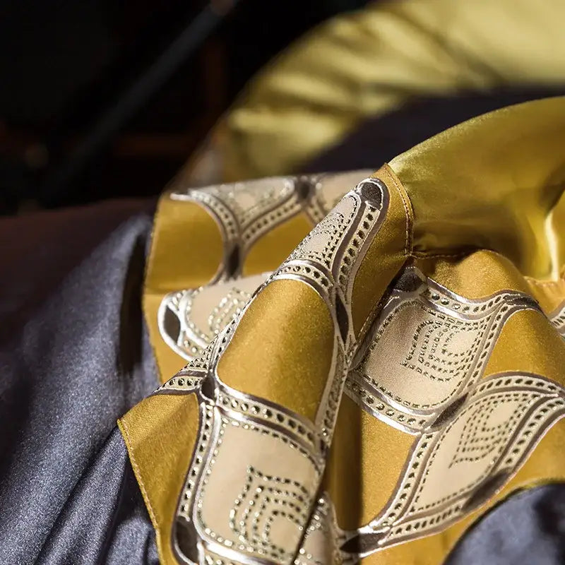 A luxurious gold satin scarf with cream silver geometric beaded detailing complements a 200s embroidery egyptian cotton bedding set