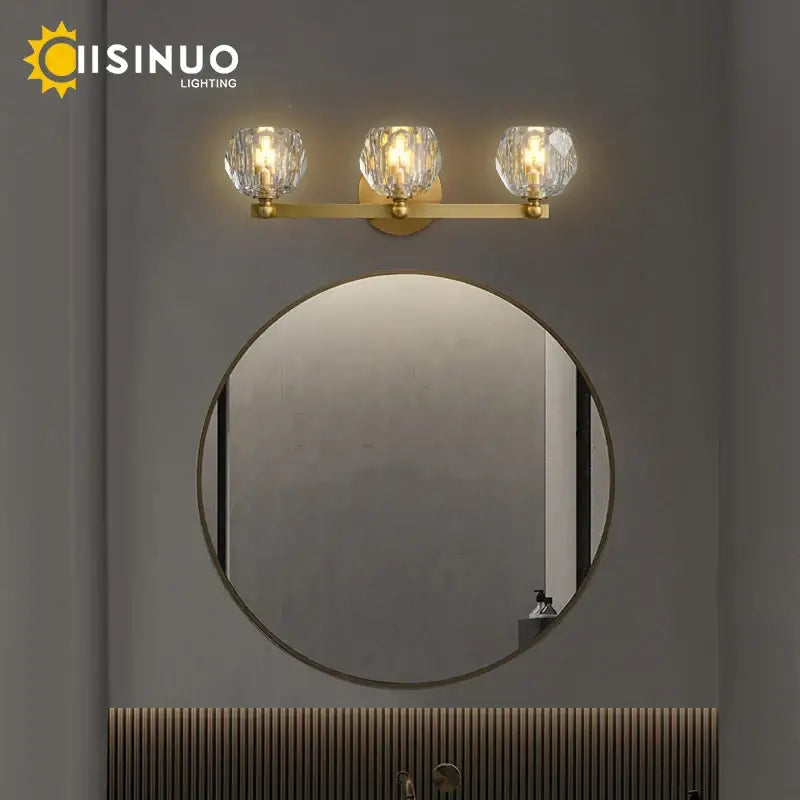 Gold-toned brass vanity light fixtures with three faceted crystal shades for bathroom use