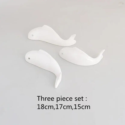 Set of three white ceramic whale figurines with glossy finish and metallic eyes complementing decorbites carp fish lotus wall art
