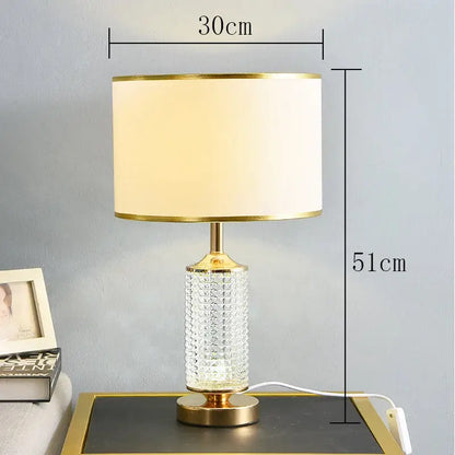 Elegant gold-toned table lamp with decorbites clear crystal faceted glass base and cream fabric shade for bedroom decor