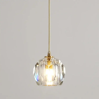 A clear faceted crystal copper led pendant light with gold toned metal fixture for dining room illumination