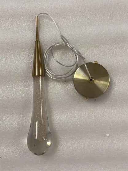 A gold liquid crystal drop pendant light with clear teardrop glass and gold-toned metal base for bedroom decorbites crystal drop