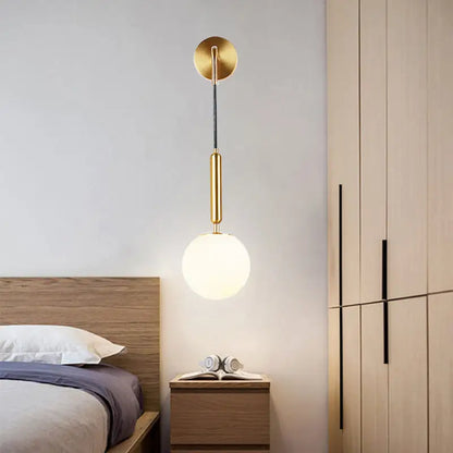 Gold-toned opal glass spherical wall light fixture with sleek cylindrical stem for bedroom use