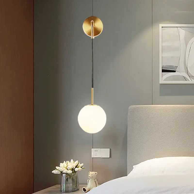 Gold opal glass spherical wall light fixture with gold-toned matte finish ideal for bedroom lighting needs