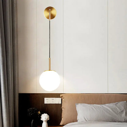 Gold opal glass spherical wall light fixture with frosted glass globe and gold-toned minimalist design for bedroom