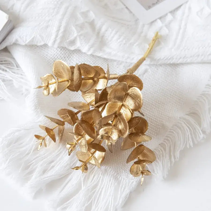 Golden faux eucalyptus leaves with metallic finish and slender stem on white fabric for decorbites eucalyptus leaves artificial plants decor