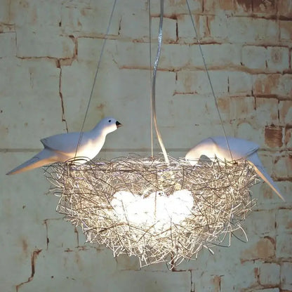 Gold and silver bird’s nest pendant lights with woven metal wire and two white bird sculptures for dining room lighting