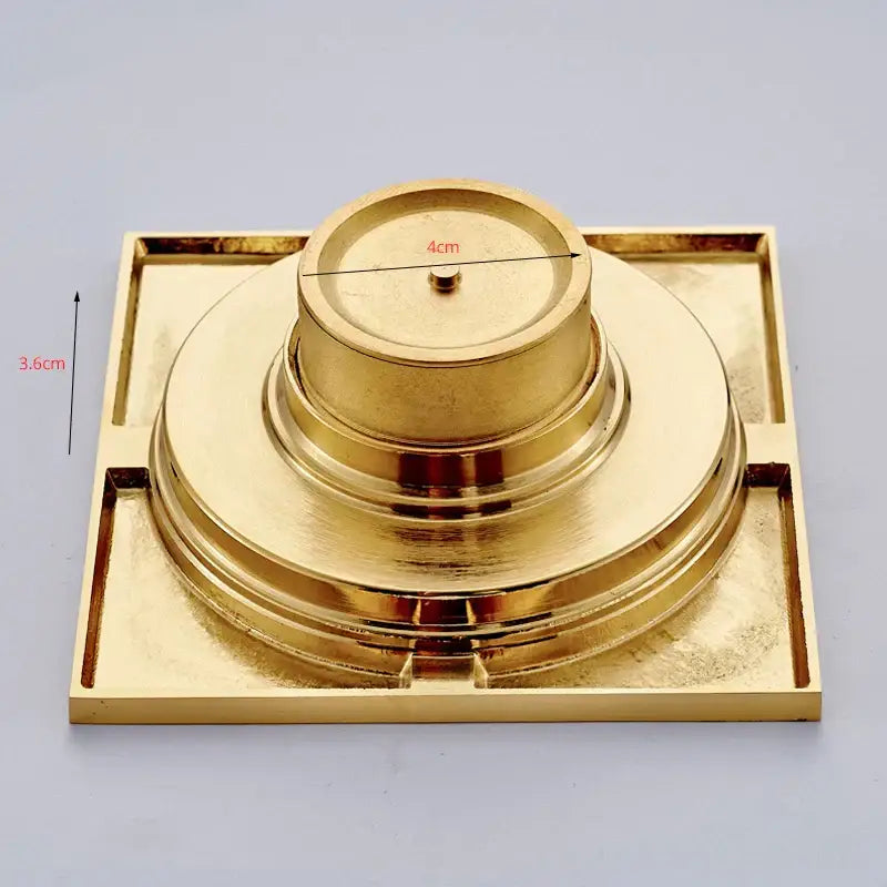 Gold-colored brass square bathroom shower drain with a central circular grate from decorbites gold square collection