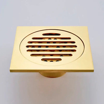 Gold square bathroom shower drain with interchangeable grates featuring a gold-colored square floor drain and circular grille