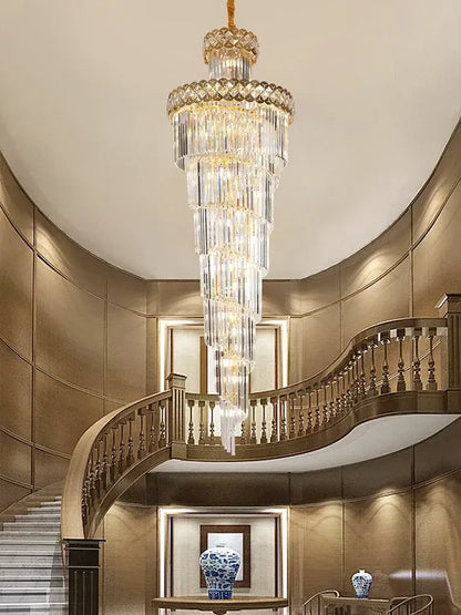 A gold stainless steel crystal chandelier with cascading clear glass prisms hanging as a staircase pendant light