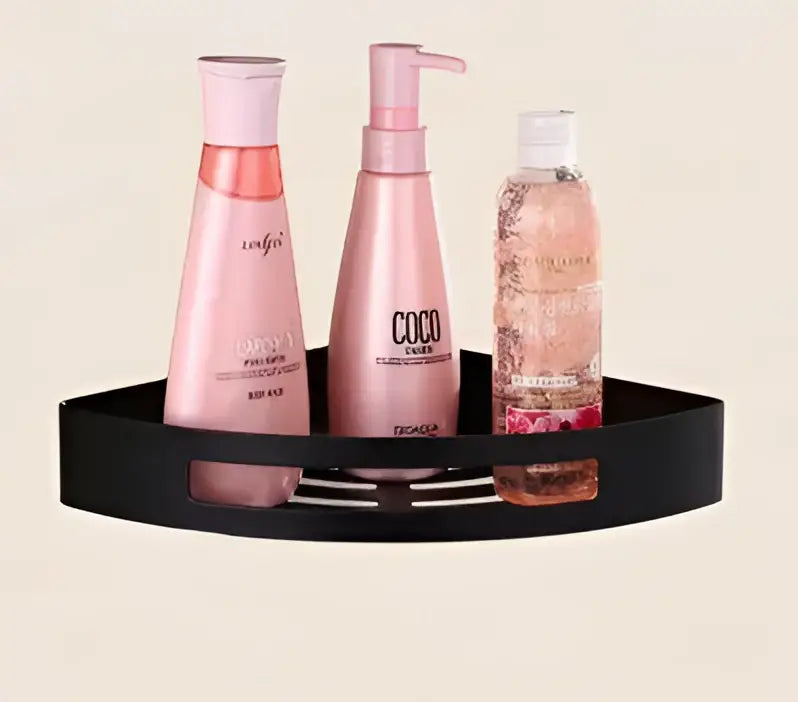 Black triangular wall-mounted decorbites gold stainless steel corner shelf holding three pink and clear hair care bottles