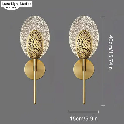 Gold finished led wall lamp with intricate textured glass panels and sleek metallic stem for indoor lighting in bedroom