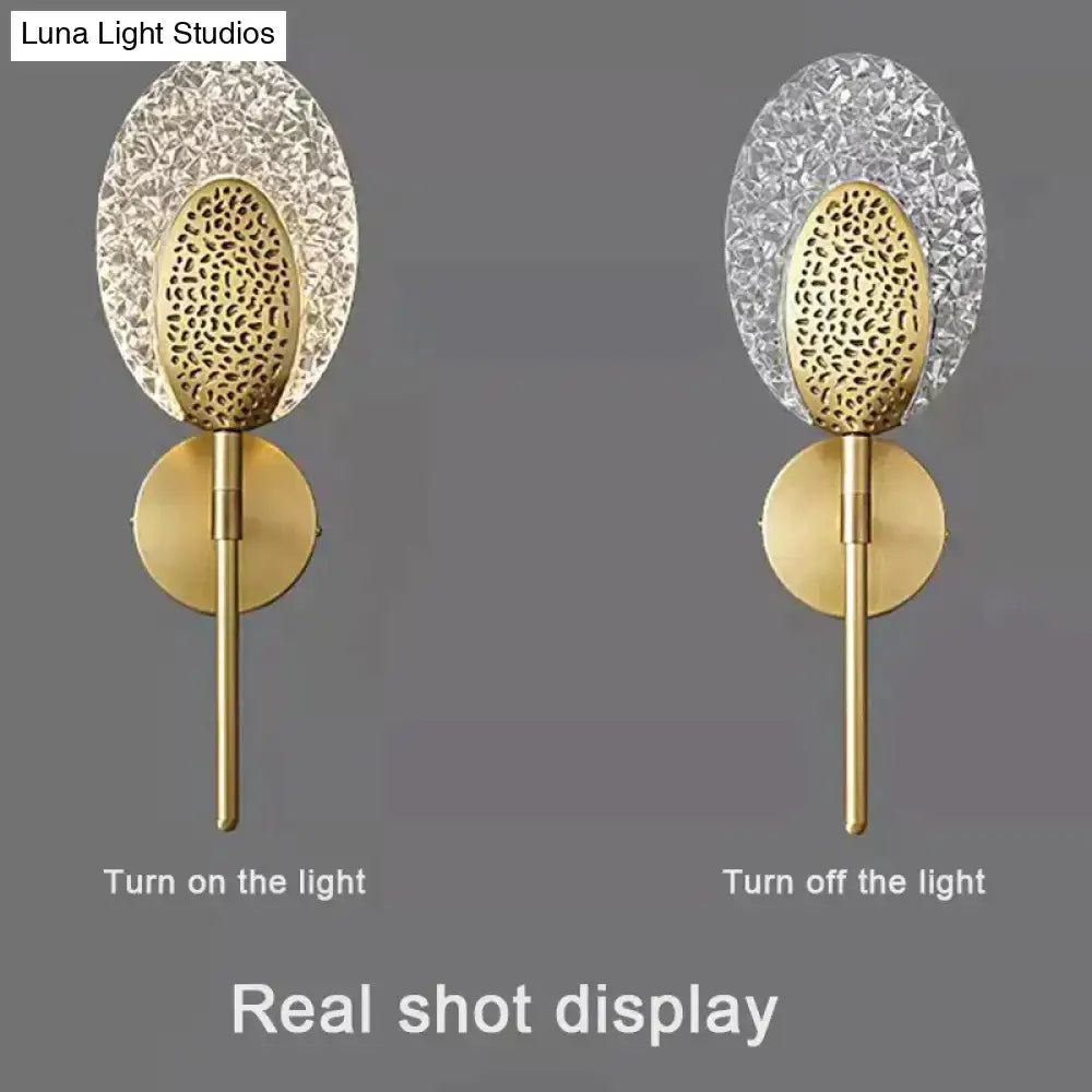 Gold finished led wall lamp with textured oval crystal shade and intricate cut-out pattern for indoor lighting