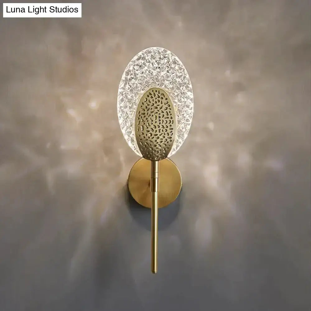 Gold textured glass led wall lamp with oval crystal diffuser and patterned metal center for indoor lighting