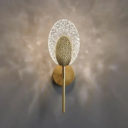 Gold-toned led wall lamp with textured glass crystal diffuser and patterned metal center for indoor lighting