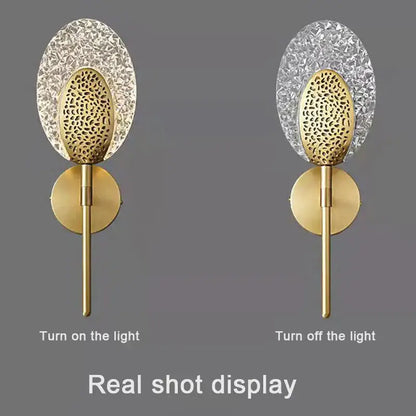 Gold-toned led wall lamp with textured glass oval crystal backplate and patterned disc for indoor lighting in bedroom