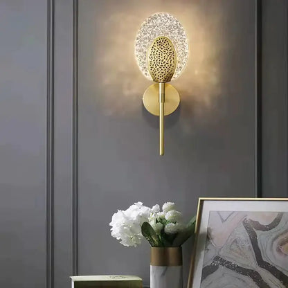 Gold-toned led wall lamp with textured glass shade and patterned metal center for indoor lighting in bedroom