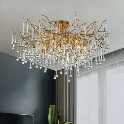 Gold tree branch chandelier with intricate metalwork and clear crystal droplets for elegant dining room lighting