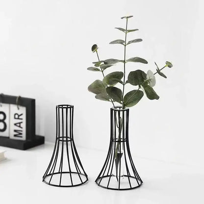 Black metal wireframe vase with flared base holding green eucalyptus branches for modern desk gold vase decoration