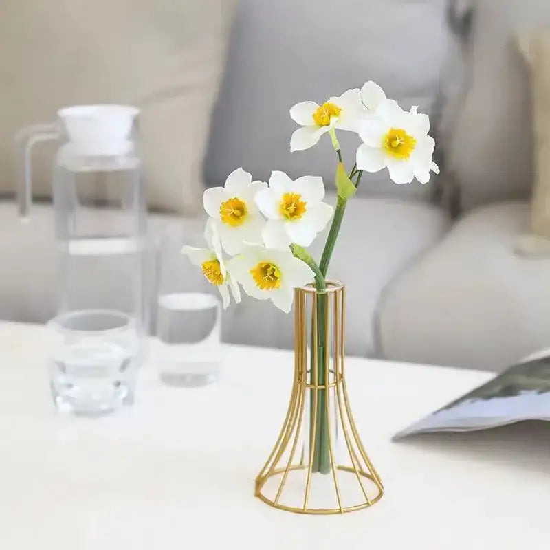 Slender gold vase made of metal wireframe holding white and yellow metal flowers for modern desk decoration