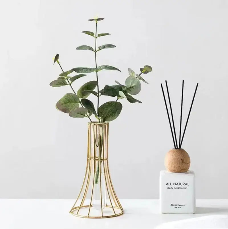 Gold vase metal flowers with eucalyptus branches as modern desk decoration in a gold wireframe design