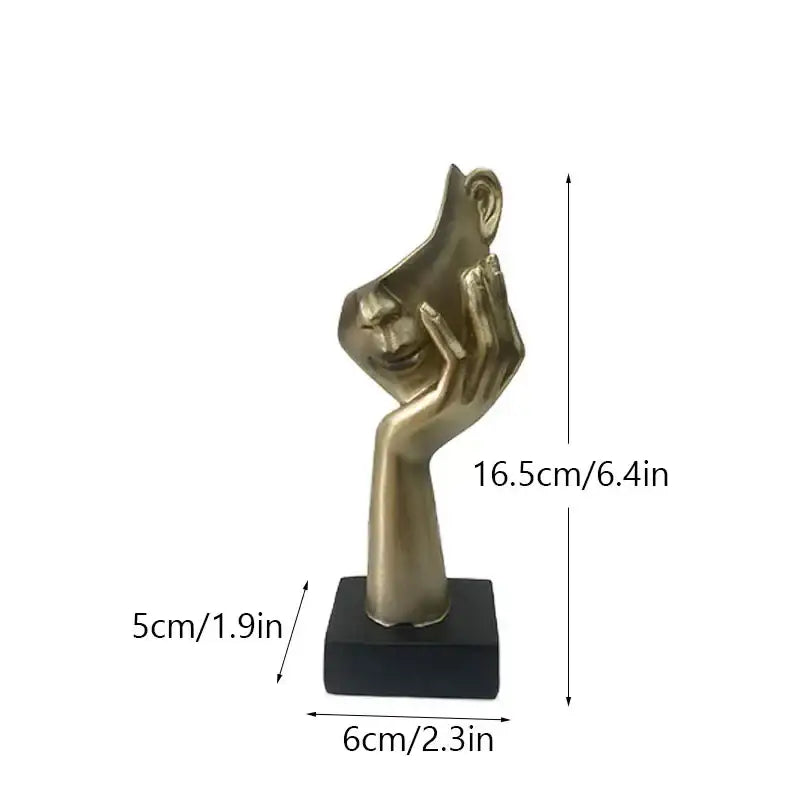 Golden metallic abstract mask statue featuring a hand cradling a smiling face on a black base for home office decor