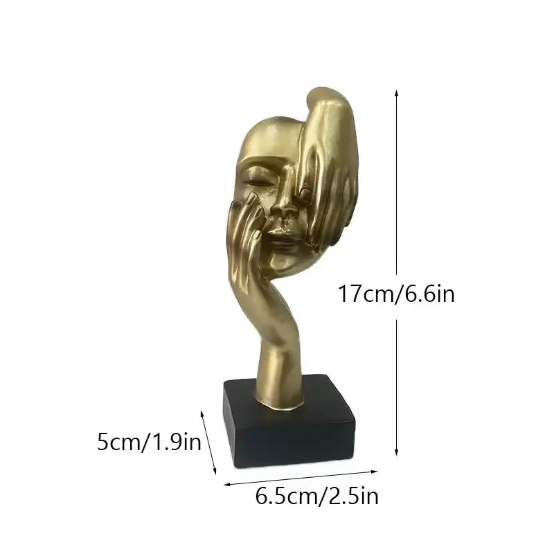 Golden abstract mask statue featuring a sculptural face with hands on a black rectangular base for home office decor