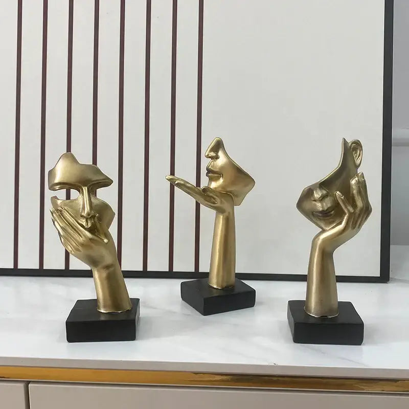 Three golden abstract mask statues mounted on black bases for elegant home office decor display