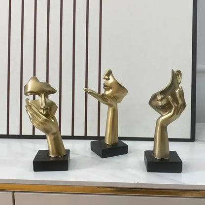 Three golden abstract mask statues mounted on black bases for elegant home office decor display