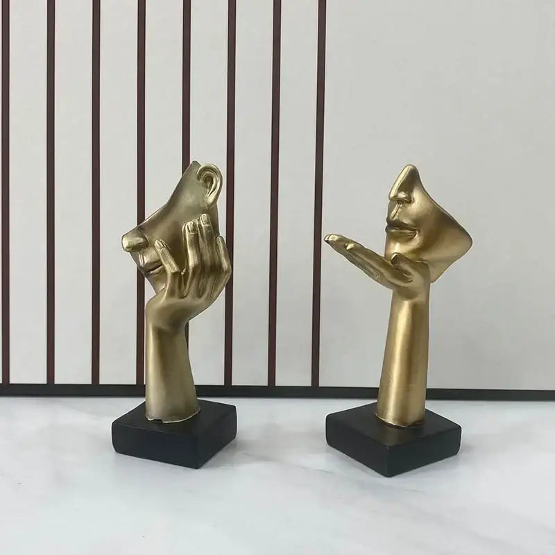 Two golden hand and face abstract mask statues on black square bases for home office decor