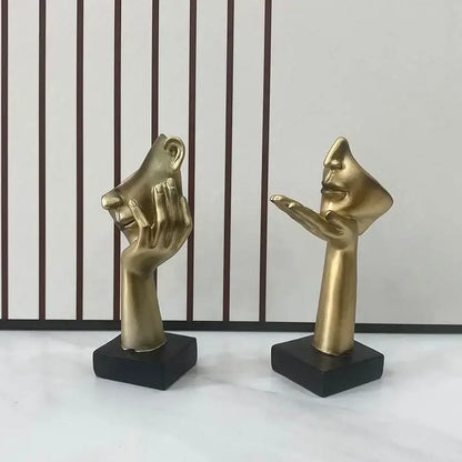 Two golden hand and face abstract mask statues on black square bases for home office decor