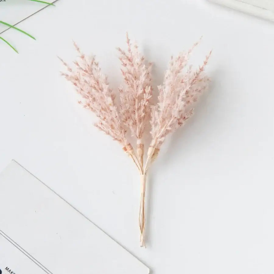A delicate bouquet of dried pink pampas grass with tan stems in a golden artificial autumn branches set decorbites decor