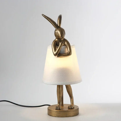 Bronze-colored decorbites bathing rabbit resin table lamp with crossed arms over white fabric shade for bedroom decor