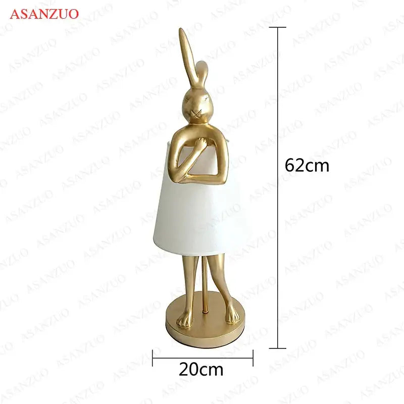 Gold-colored bathing rabbit resin table lamp wearing a white dress on circular base for bedroom decorbites decor