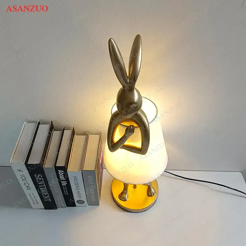 Gold-toned bathing rabbit resin table lamp with frosted glass shade and circular base for bedroom decorbites decor