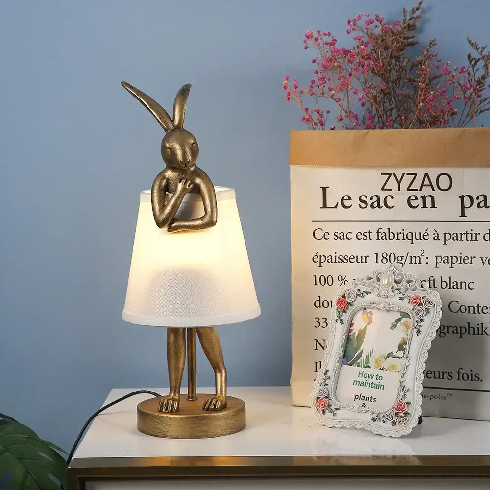 Golden bathing rabbit resin table lamp with white fabric shade and standing legs for bedroom decorbites decor