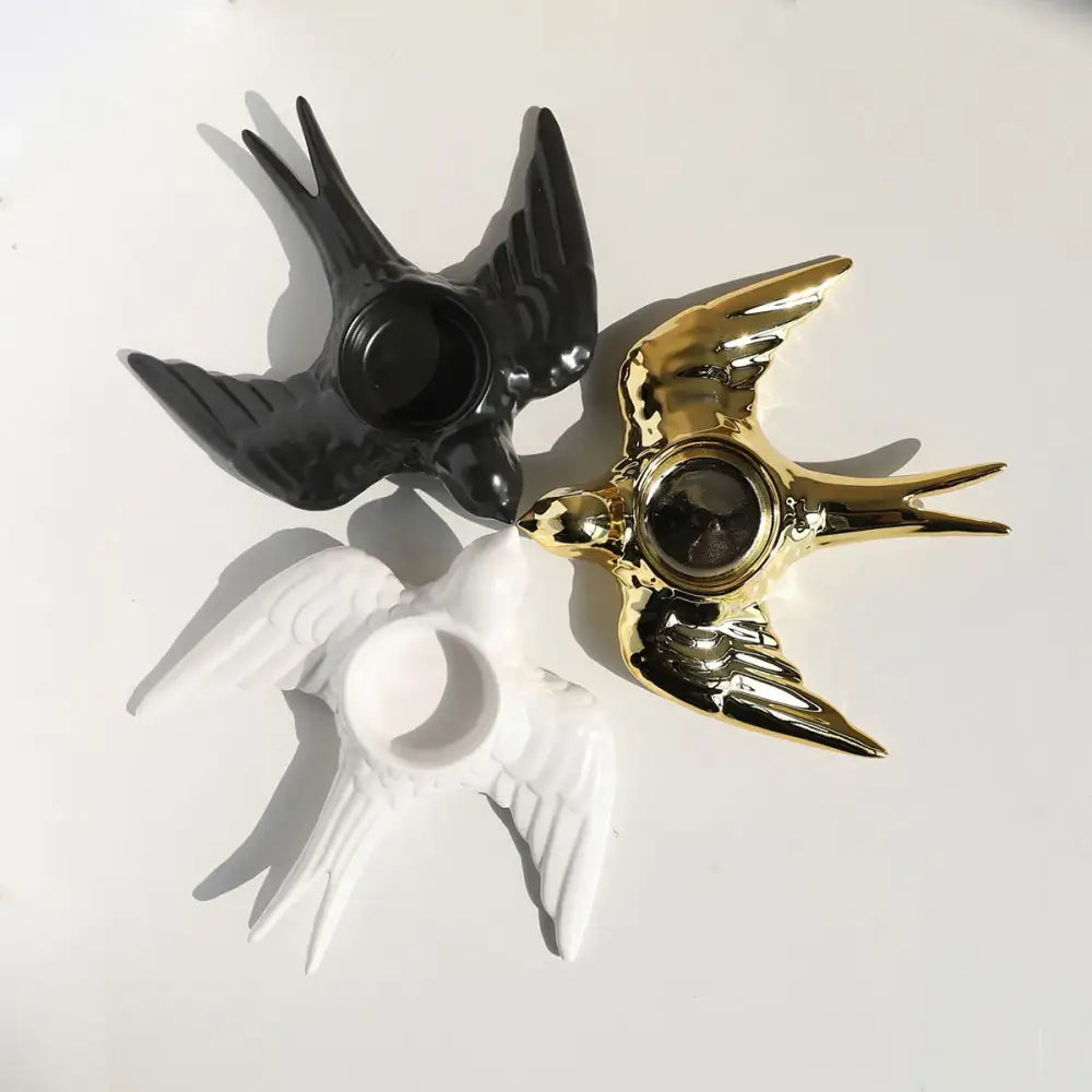 Three glossy swallow-shaped ceramic candle holders in black gold and white on a golden bird candle holder tray for wedding decor