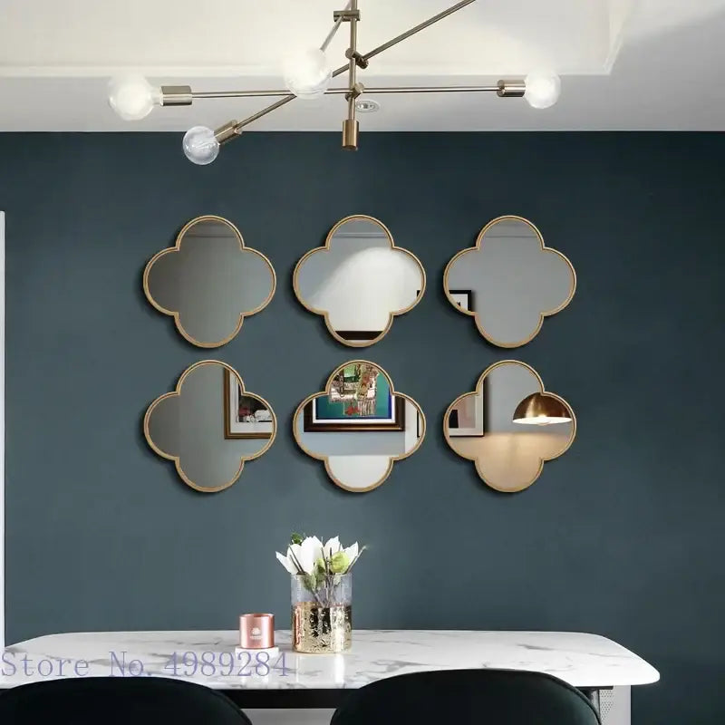 Six gold-framed geometric plum flower quatrefoil mirrors with golden border arranged on dark blue living room wall