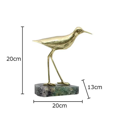 Golden brass bird desk ornament standing on a green and black marble base for living room decor